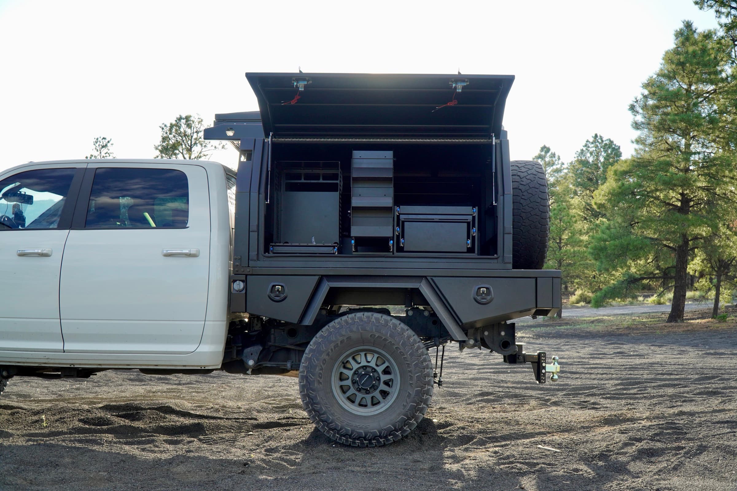 Aluminum touring canopy on Ram 2500 with side door open showing interior storage