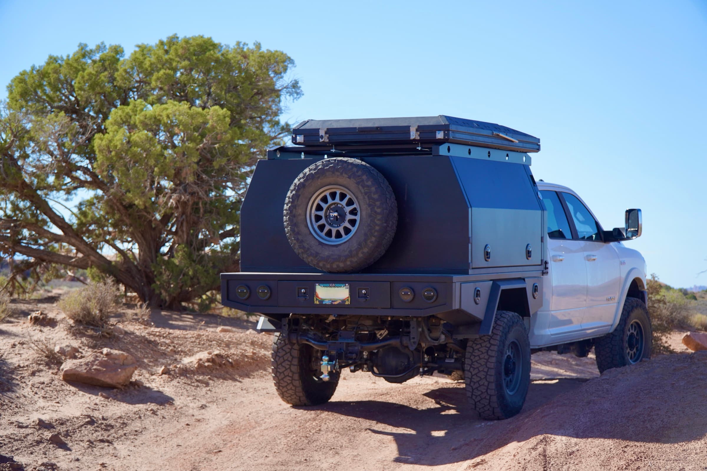 Ram 2500 with sealed touring canopy and tray in a red-dirt overland setting