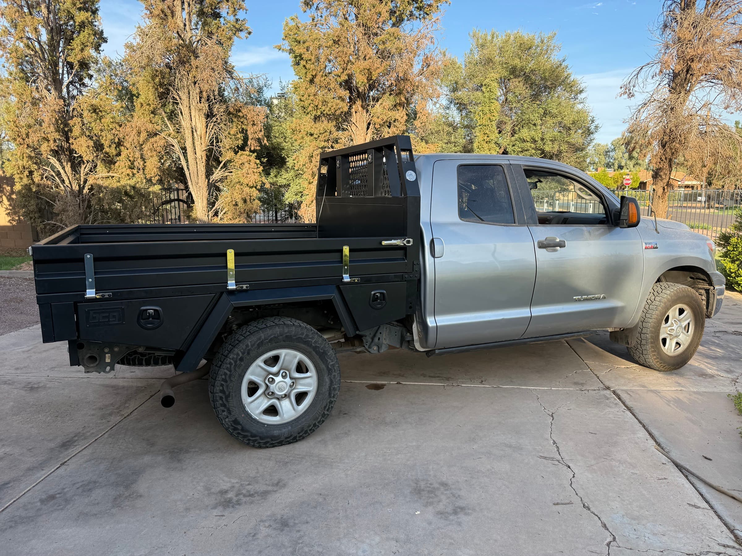 Silver 2013 Toyota Tundra Double Cab with a black aluminum flatbed tray, fold-down dropsides, and a mesh headboard