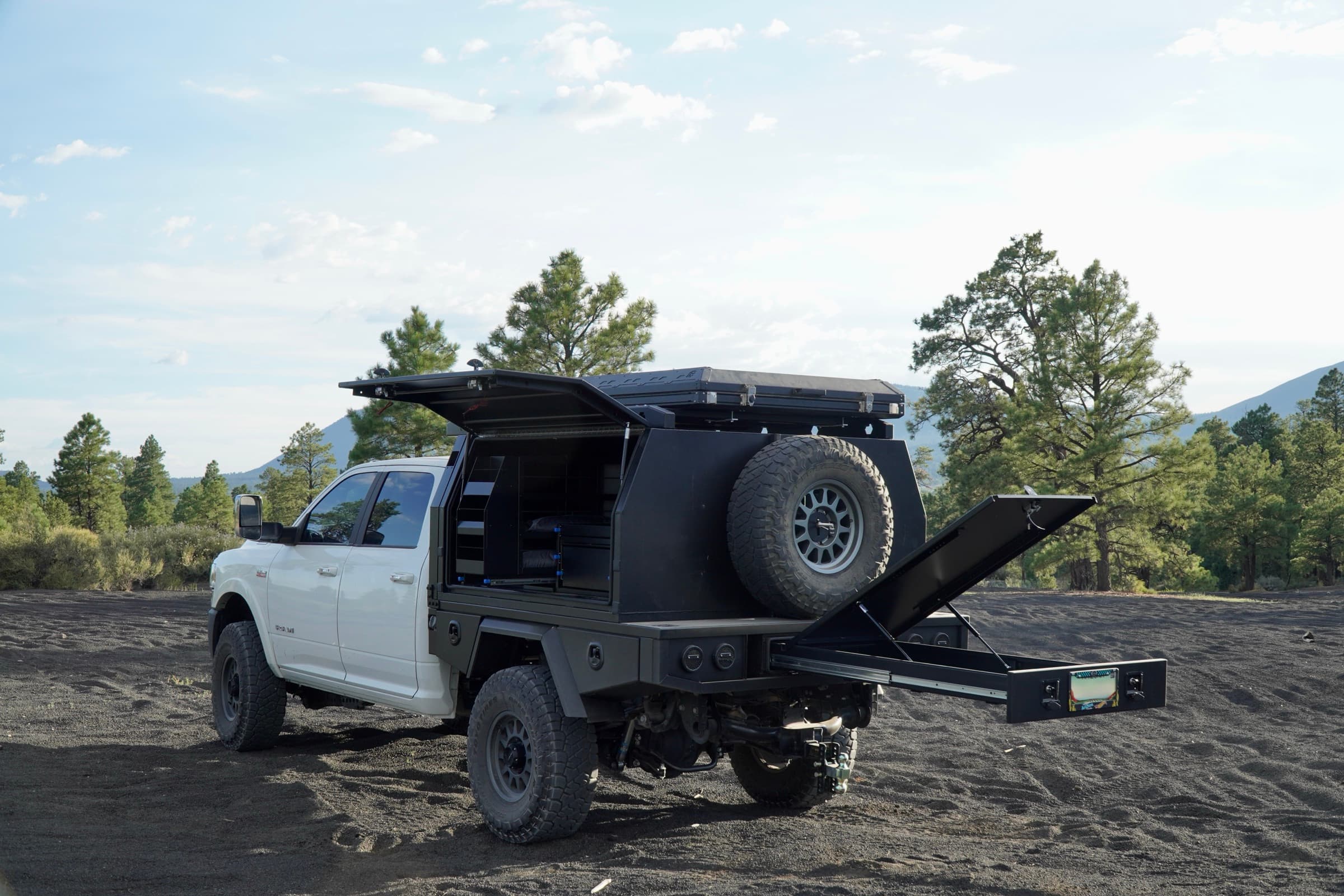 Ram 2500 with aluminum UTE tray and touring canopy in a pine forest at golden hour