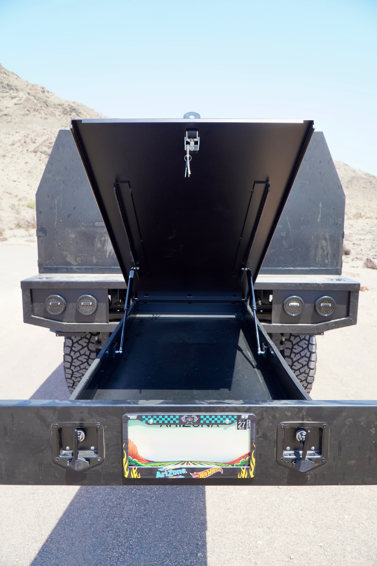 Rear view of the Ram 3500 with both canopy gullwing doors raised, showing the centre storage tunnel and recessed rear light pods