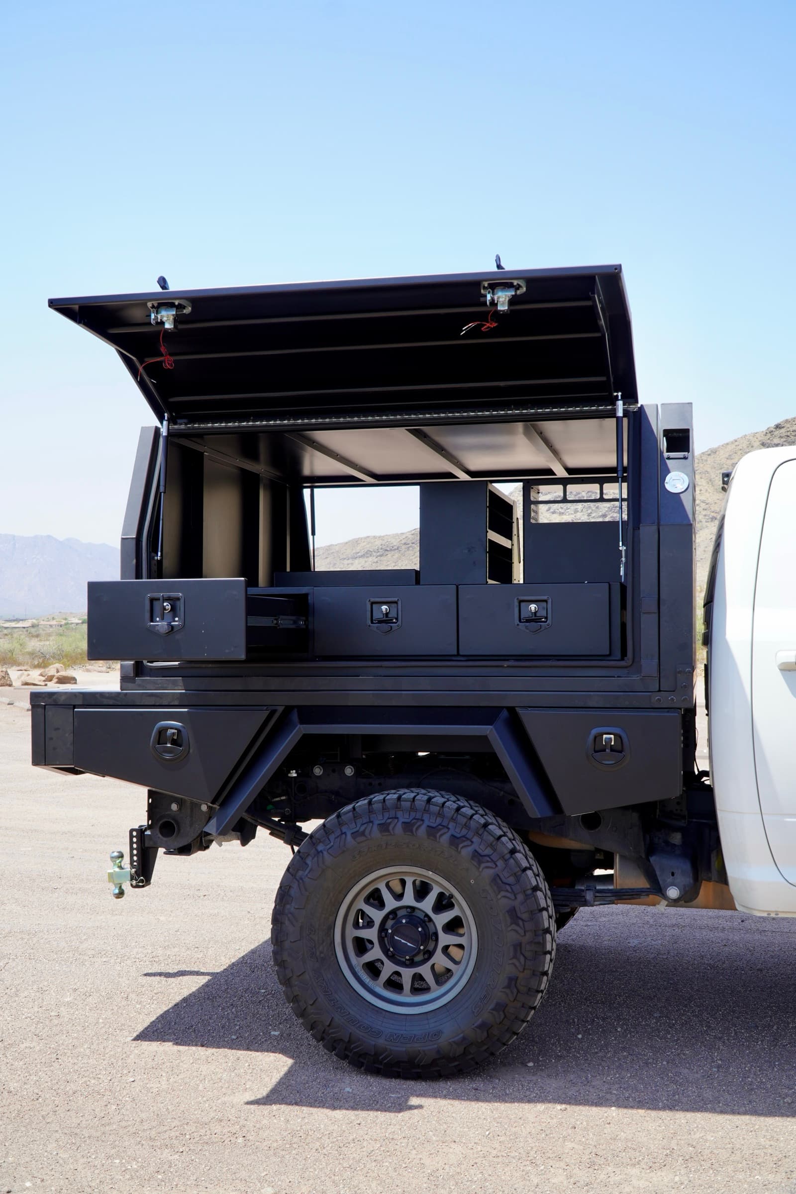 Side profile of the Ram 3500 touring canopy with the gullwing door raised and three slide-out drawers visible